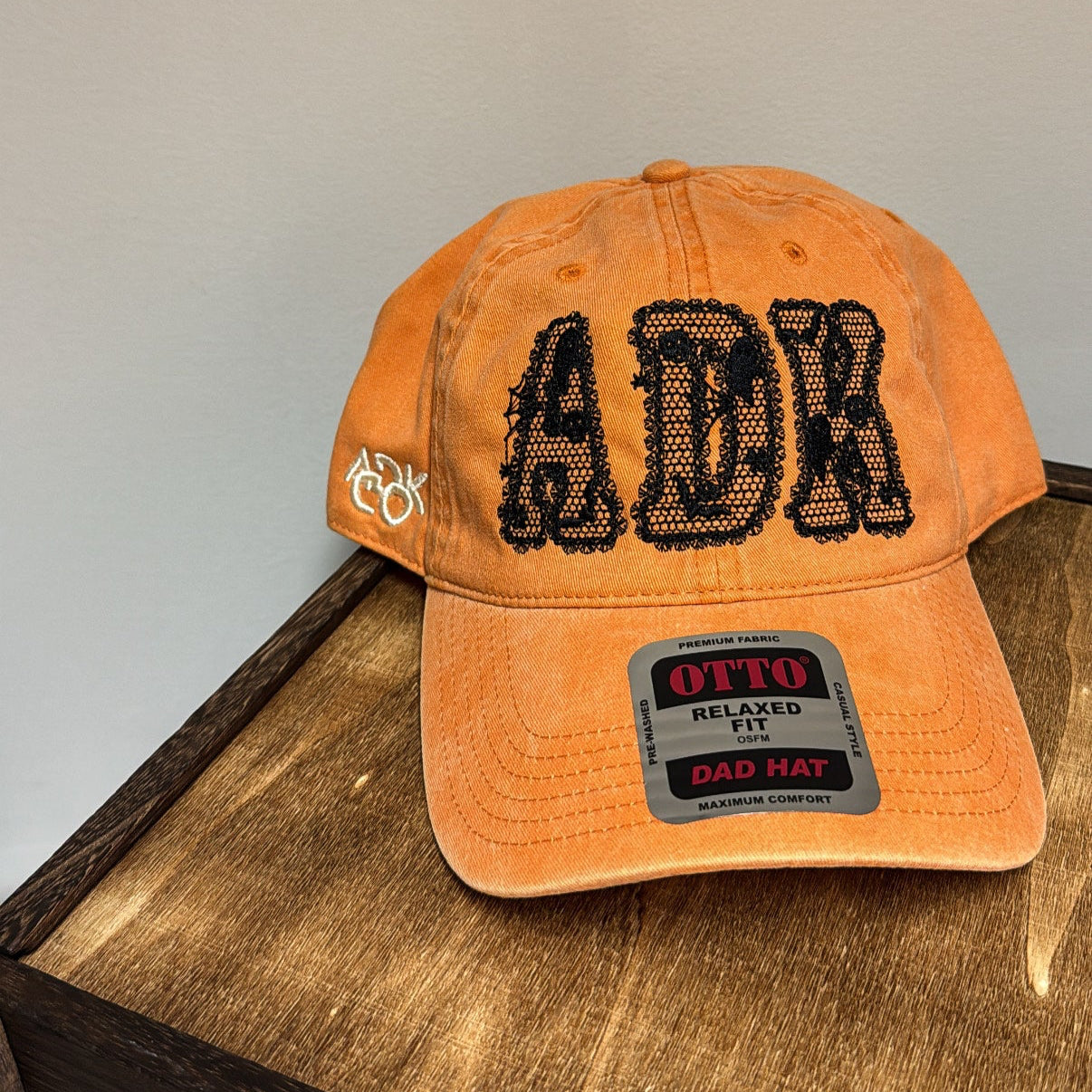 Orange cap with black text and branding on a wooden surface