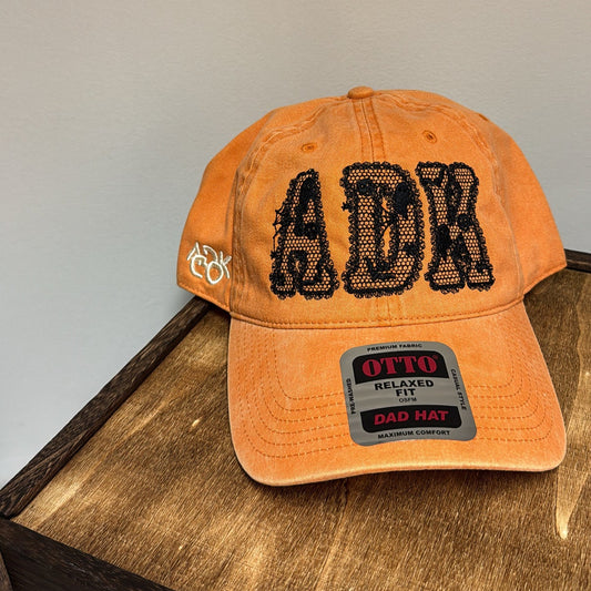 Orange cap with black text and branding on a wooden surface